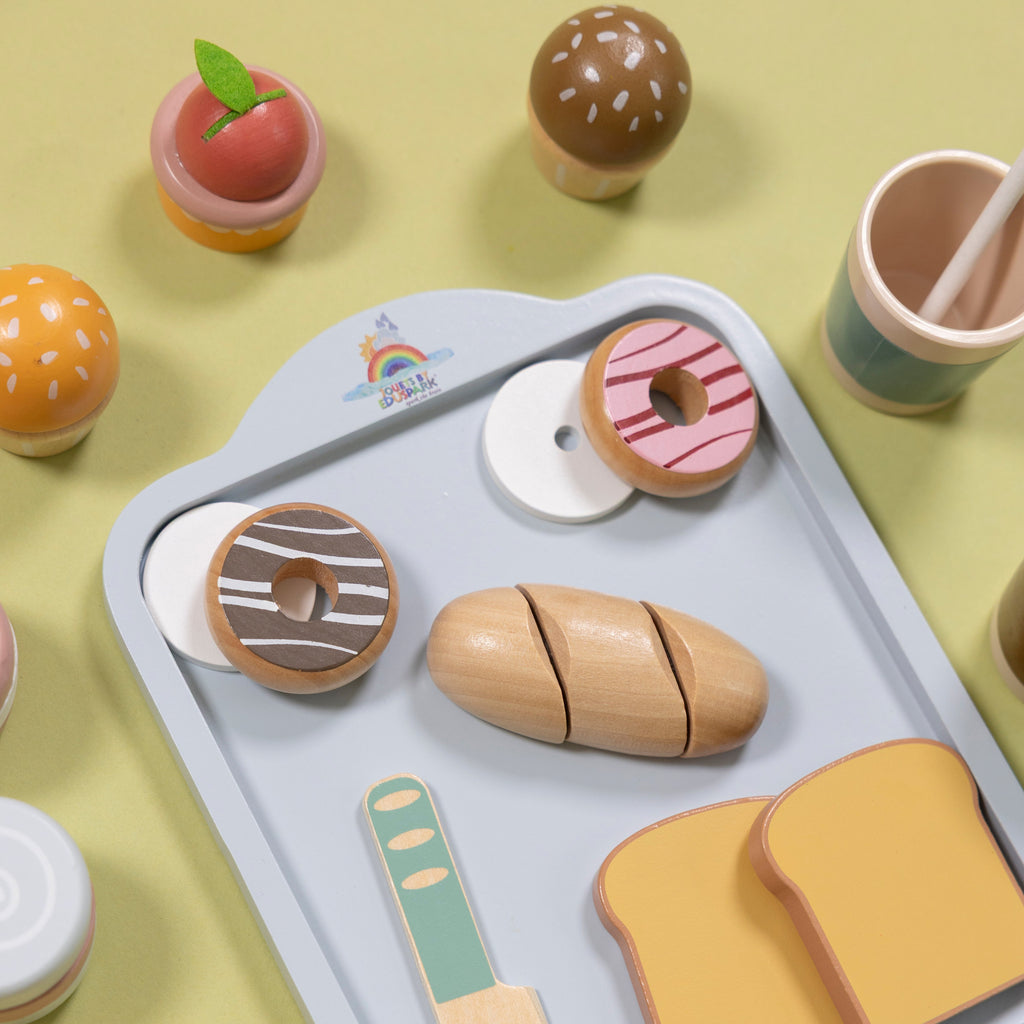 Wooden toy food set on a tray with a green background